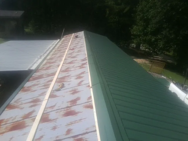 Old rusted panels beside newly installed green metal roofing — Wind Damage Roof Repair by Roofing Brothers in Dudley