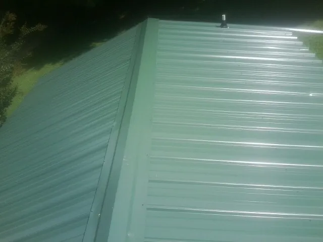 New green metal panels meeting at the ridge of a roof — Flat Roof Repair work by our crew in Dudley