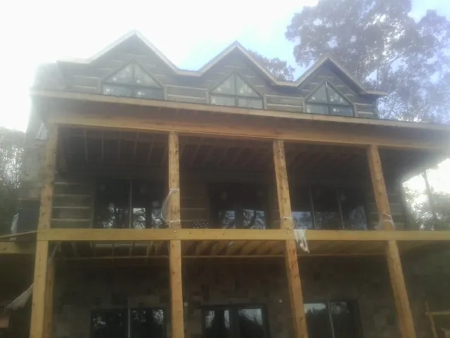Dormers and porch framing on a large log home under construction — Roof Coating work by our crew in Dudley