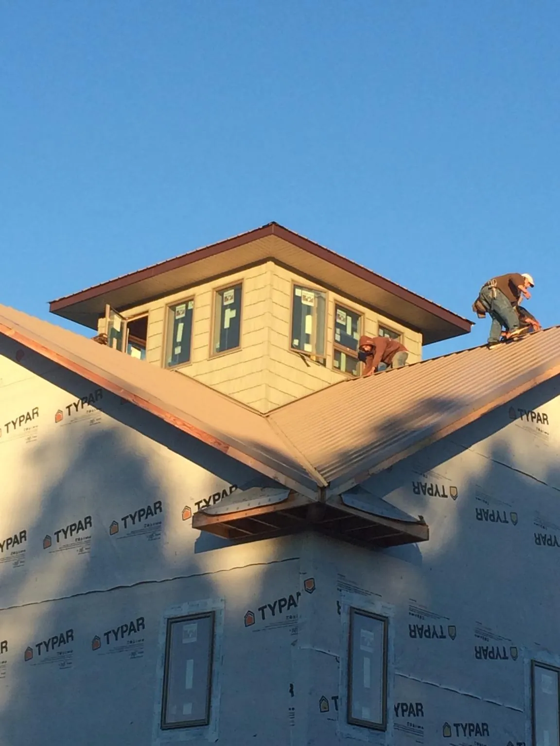 Roofers working around a rooftop cupola on a new metal roof at sunset — Roof Waterproofing in Dudley by Roofing Brothers